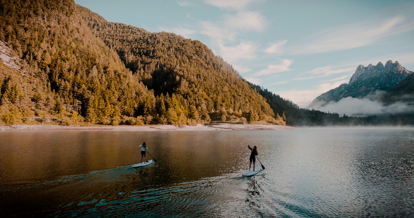 Rider on electric paddleboard with instructor on Montana lake in Glacier National Park – eSUP session booking at MontanaBoardingSchool.com. Rent from MTBoarders.com or buy from E-Boarders.com