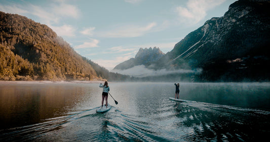 Rider on electric paddleboard with instructor on Montana lake in Glacier National Park – eSUP session booking at MontanaBoardingSchool.com. Rent from MTBoarders.com or buy from E-Boarders.com
