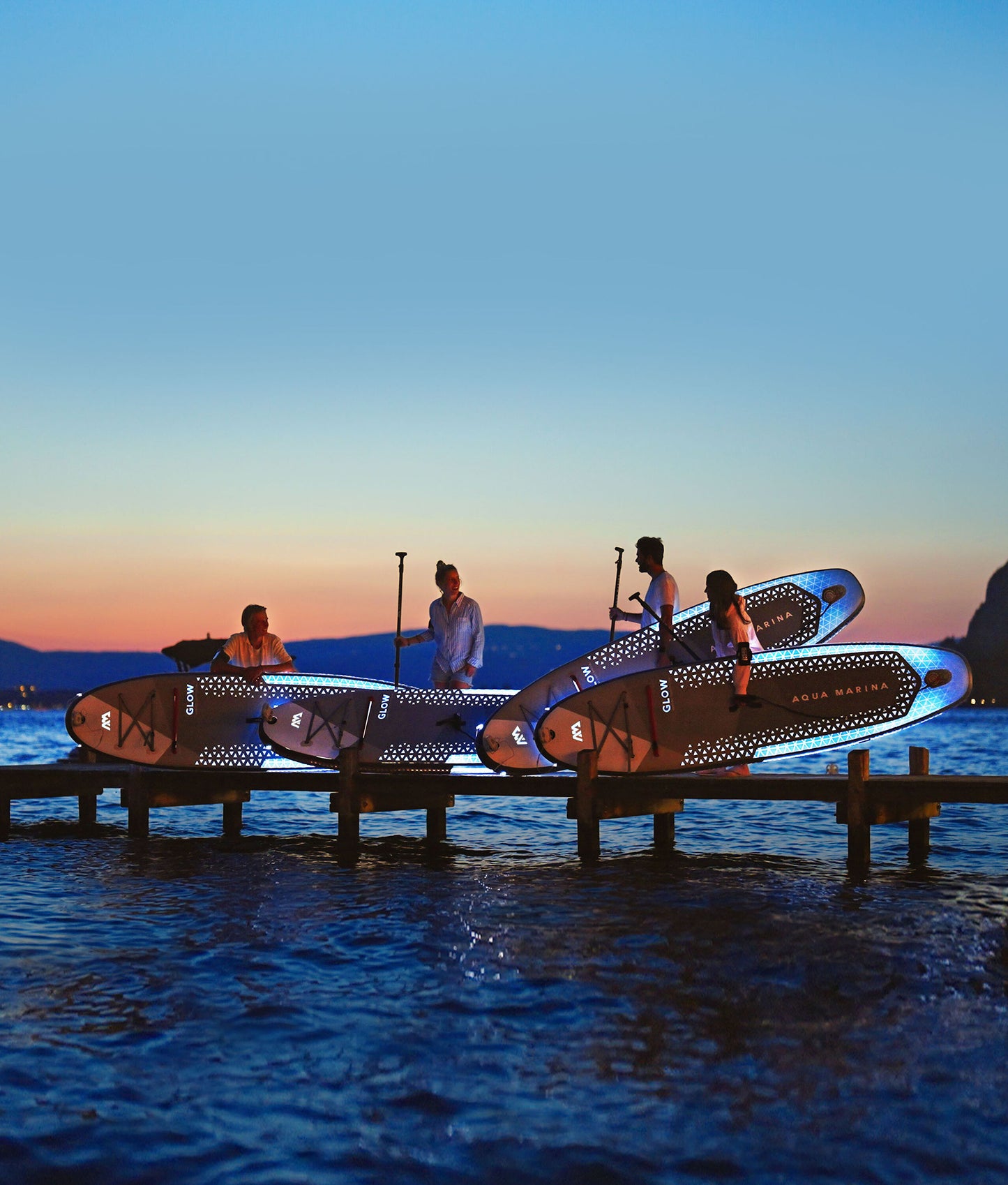 Group of paddleboarders glowing on the lake under moonlight during a night session – book a moonlight paddle party at MontanaBoardingSchool.com. Rent full daily and weekly rates at MTBoarders.com or buy now from eboarders.com
