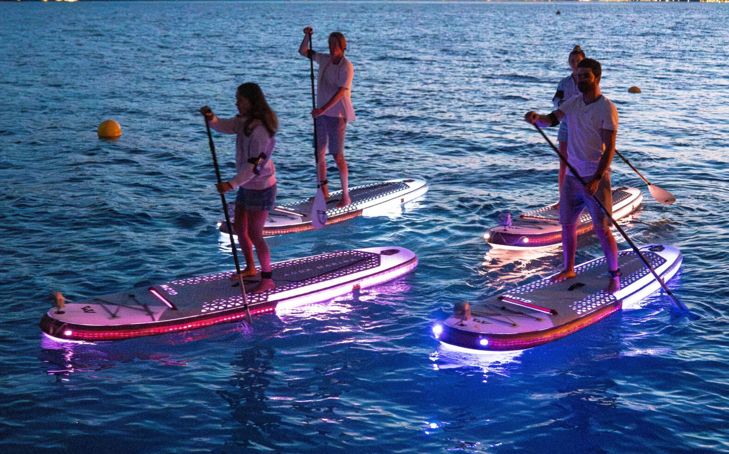 Group of paddleboarders glowing on the lake under moonlight during a night session – book a moonlight paddle party at MontanaBoardingSchool.com. Rent full daily and weekly rates at MTBoarders.com or buy now from eboarders.com