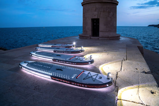 Group of paddleboarders glowing on the lake under moonlight during a night session – book a moonlight paddle party at MontanaBoardingSchool.com. Rent full daily and weekly rates at MTBoarders.com or buy now from eboarders.com