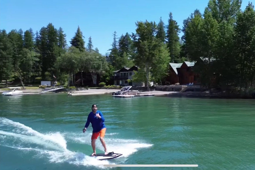 Person Jetboarding on Flathead Lake with trees and cabins in the background